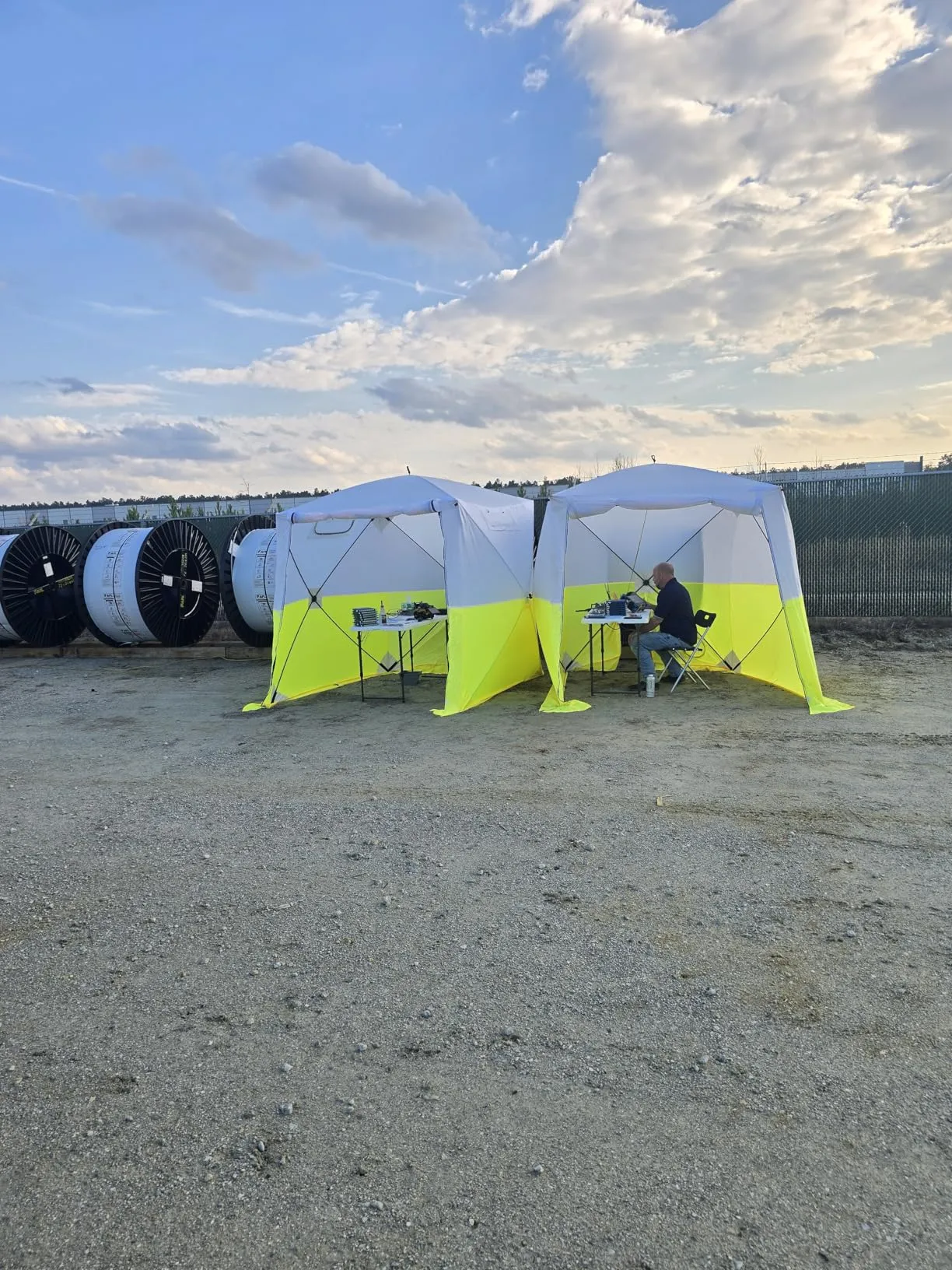 Deux tentes de chantier JAX3 déployées sur un site de tirage de câble, tourets à l'arrière